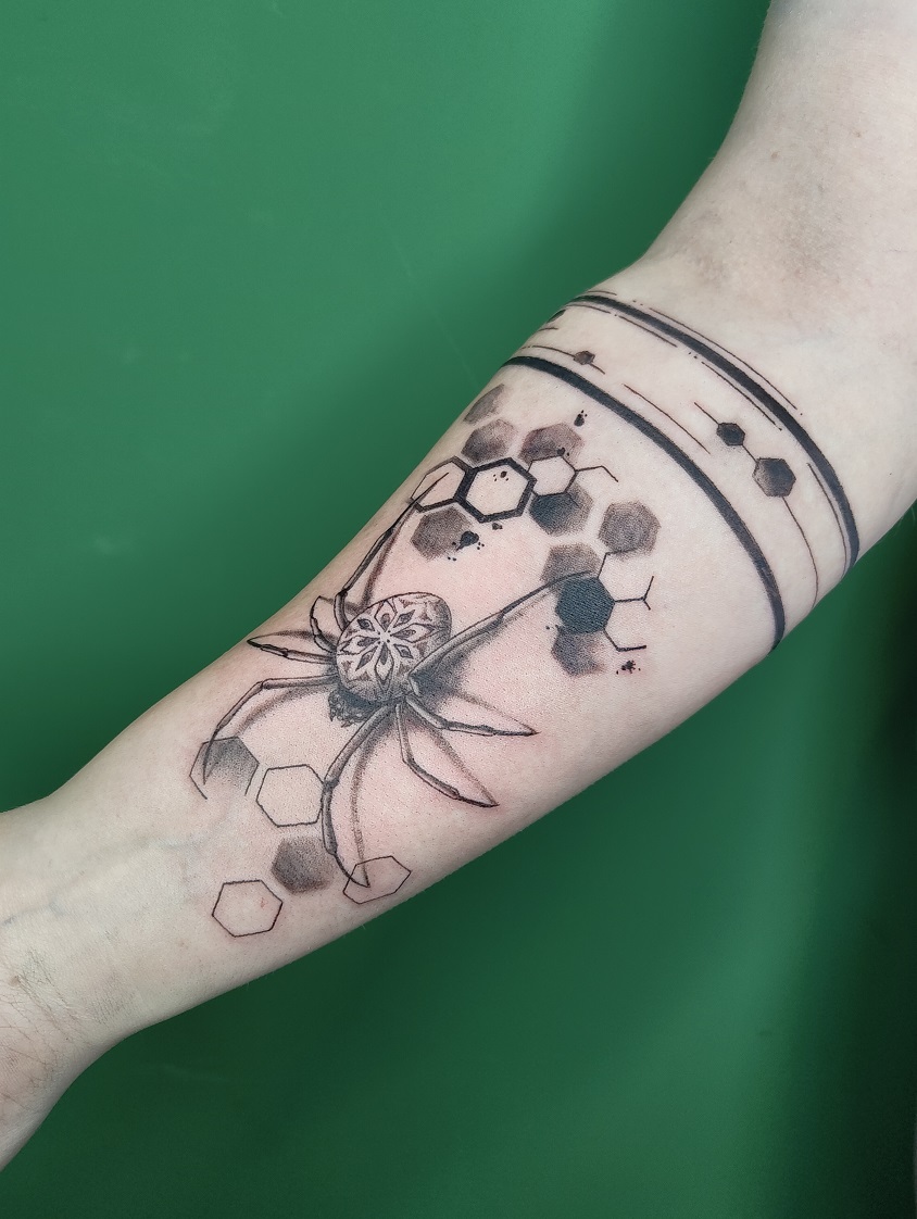 Tattoo einer realistischen Spinne mit Hexagon-Elementen und ein Band mit Hexagon-Elementen um den Unterarm